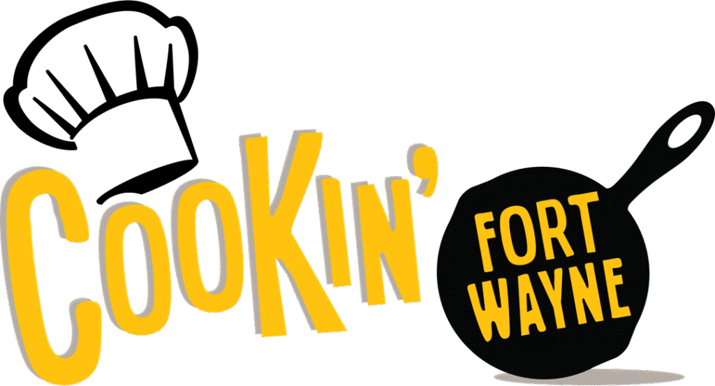 Cookin' Fort Wayne logo with a yellow wordmark, a chef's hat on the left, and a black skillet on the right.